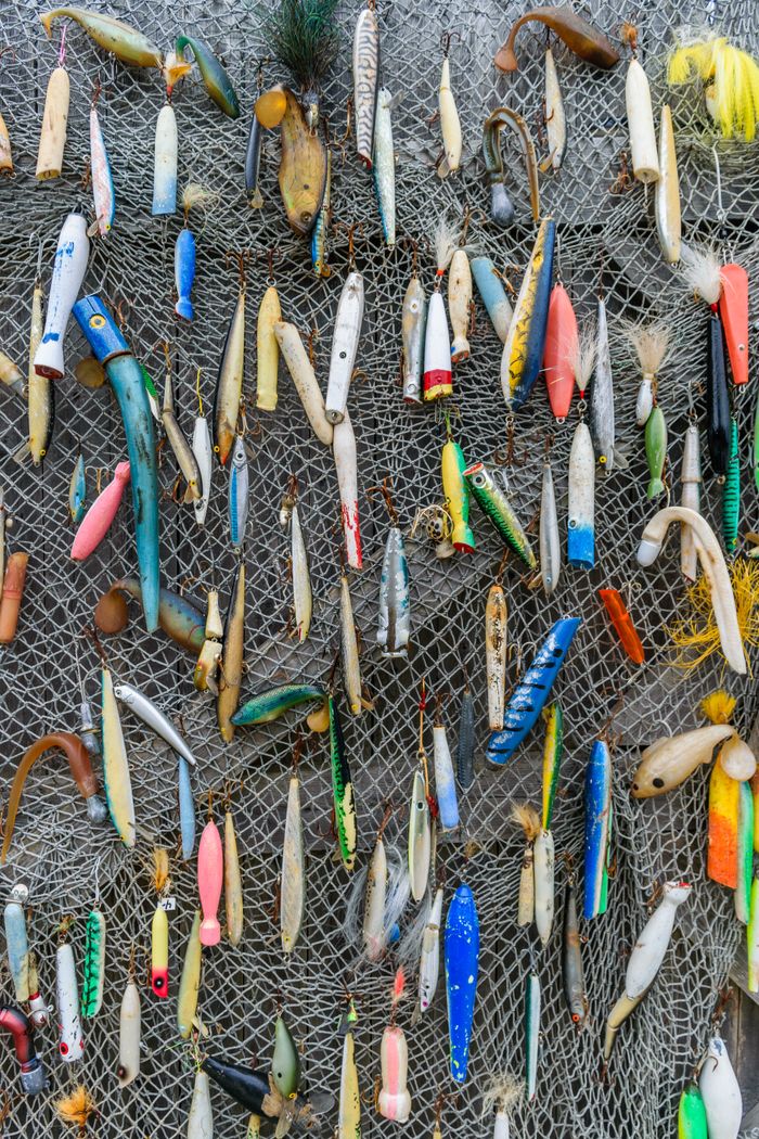 A vibrant collection of fishing lures and hooks hanging on a net, showcasing variety and color.