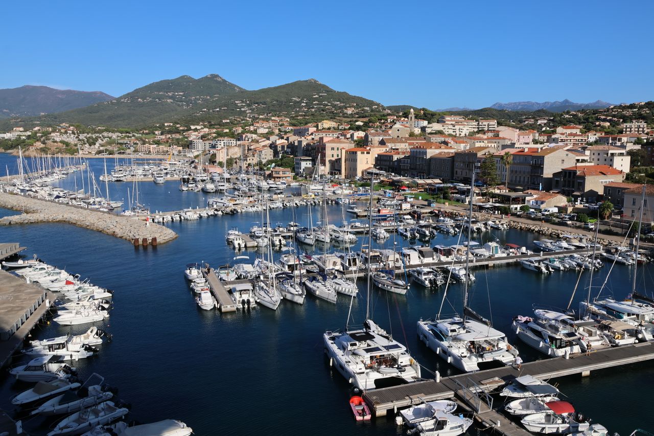 Charming harbor filled with sailboats and yachts against a backdrop of hills and a coastal town.